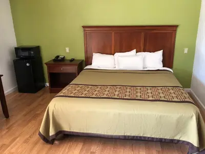 a bedroom with a large bed with a wooden headboard at Americas Best Value Inn Visalia in Visalia