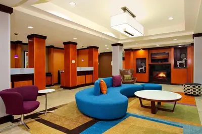 a lobby with a blue couch and chairs and a fireplace at Fairfield Inn & Suites Fresno Clovis in Clovis