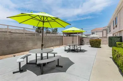 two tables and two yellow umbrellas on a patio at Comfort Suites Tulare Sequoia Gateway in Tulare