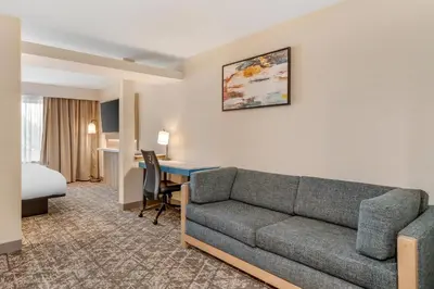 a living room with a couch and a desk in a hotel room at Country Inn & Suites by Radisson, Modesto-Salida in Modesto