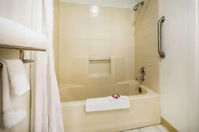 a bathroom with a bath tub with a towel on it at Super 8 by Wyndham Lindsay Olive Tree in Lindsay