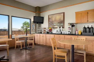 a kitchen with two tables and chairs and a counter at Super 8 by Wyndham Lindsay Olive Tree in Lindsay