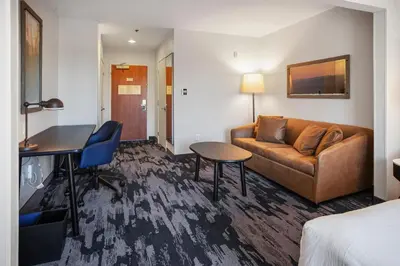 a hotel room with a couch and a table at Fairfield Inn & Suites Rancho Cordova in Rancho Cordova