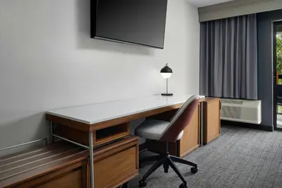 a desk with a chair and a television on a wall at Courtyard by Marriott Stockton in Stockton