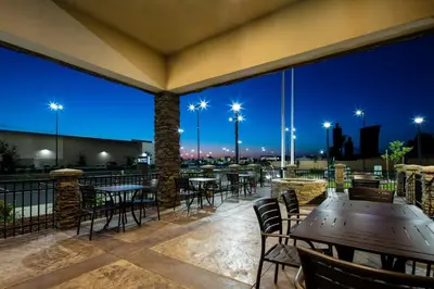 a patio with tables and chairs at night at Hyatt Place Delano in Delano