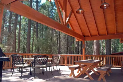a wooden deck with tables and chairs and trees at 26 Deer Den in North Wawona