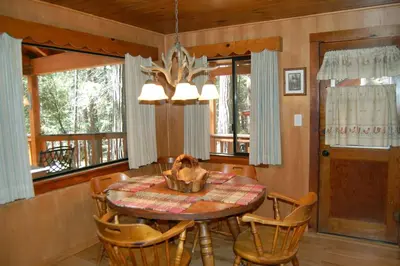 a dining room with a table and chairs and windows at 26 Deer Den in North Wawona