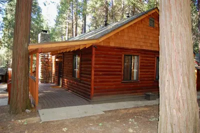 a log cabin with a deck in the woods at 26 Deer Den in North Wawona