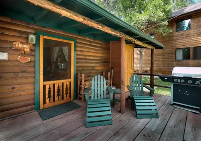 a cabin with chairs and a grill on a deck at 14 Chipmunk Hollow in Wawona