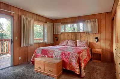 a bedroom with a bed with a red blanket and two windows at 99 Yosemite Mountain Lodge in Wawona