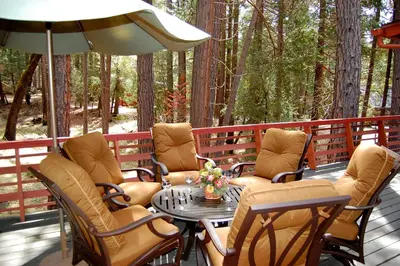 a deck with chairs and a table and an umbrella at 39 River Song in North Wawona