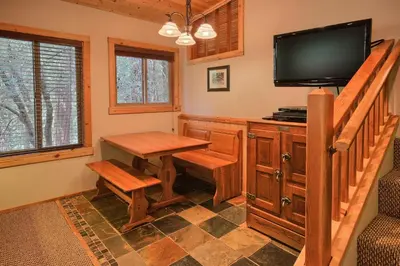 a dining room with a table and a flat screen tv at 1L The Tree House in North Wawona