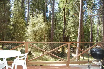 a deck with a grill and a table and chairs at 78 Ox Yoke in Wawona