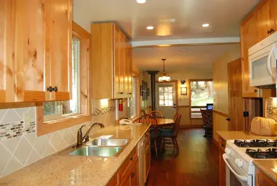 a kitchen with wooden cabinets and a sink and a table at 78 Ox Yoke in Wawona