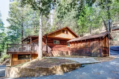 a log cabin with a deck and a house at 22B Bradleys Cabin in Wawona