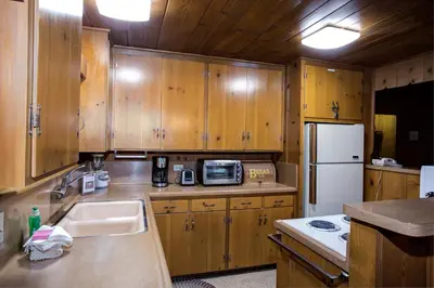 a kitchen with wooden cabinets and a sink and a refrigerator at 22B Bradleys Cabin in Wawona