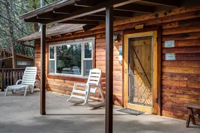 a wooden cabin with two chairs and a door at 22B Bradleys Cabin in Wawona