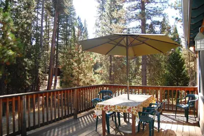 a table and chairs on a deck with an umbrella at 9N Fox Hollow in Wawona
