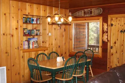 a dining room with a green table and chairs at 76 Howards Retreat in North Wawona