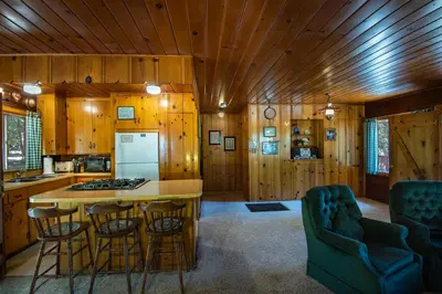 a kitchen with wooden walls and a kitchen island with bar stools at 3N Lockwood Lodge in Wawona