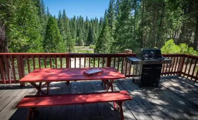 a wooden deck with a picnic table and a grill at 3N Lockwood Lodge in Wawona