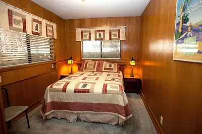 a small bedroom with a bed and two windows at 48R The Tree House II in Wawona