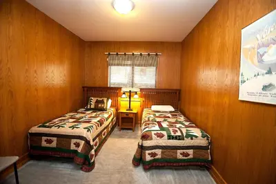 two beds in a room with wooden walls at 48R The Tree House II in Wawona