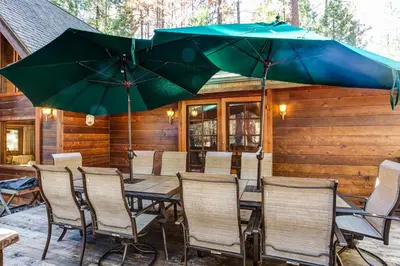 a patio with tables and chairs and umbrellas at 41A Cedar Chalet in Wawona