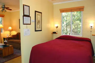 a bedroom with a red bed and a living room at 65 Sparrows Nest in Wawona