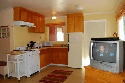 a kitchen with a white refrigerator and a tv at 65 Sparrows Nest in Wawona