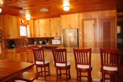 a kitchen with wooden cabinets and a counter with four chairs at 92 Harmony Villa in Wawona