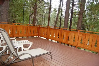 a wooden deck with two chairs and a table at 19B Yosemite Retreat in the Meadows in Wawona