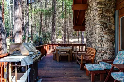 a porch of a cabin with a stove and chairs at 23B Robins Nest in North Wawona