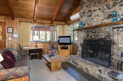 a living room with a stone fireplace and a tv at 23B Robins Nest in North Wawona