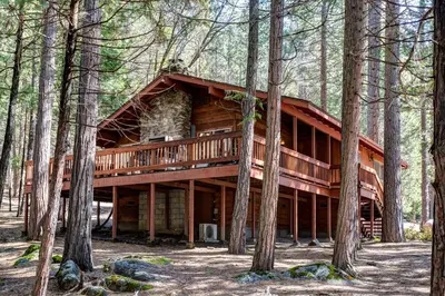 a log cabin in the woods with trees at 23B Robins Nest in North Wawona