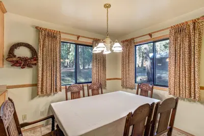 a dining room with a white table and chairs and windows at 12 Cabin Twelve in Wawona