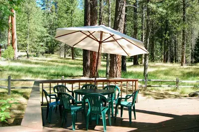 a table with chairs and an umbrella on a deck at 93R Deer Lodge in North Wawona