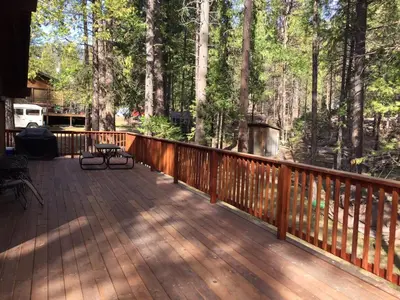 a large wooden deck with a grill and trees at 69 Bordentown West in Wawona