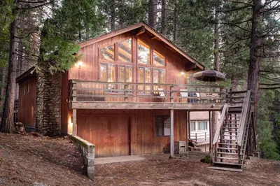 a tree house in the woods with a deck at 17B Tylers Timber Lodge in Wawona