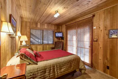 a bedroom with a bed in a room with wooden walls at 17B Tylers Timber Lodge in Wawona