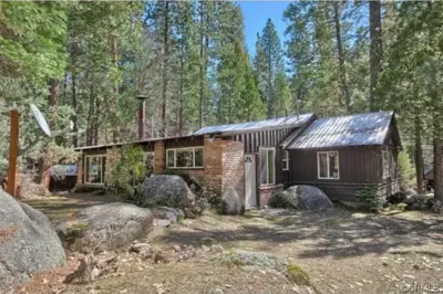 a small cabin in the woods with trees at 95R The Little Creek Cabin in Wawona