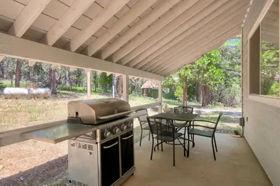 a outdoor kitchen with a grill and a table with chairs at 43R Edna's Hearts Desire in North Wawona