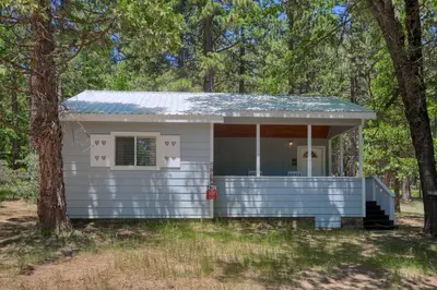 a small white house in the middle of trees at 43R Edna's Hearts Desire in North Wawona