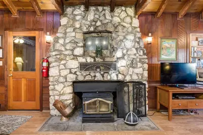 a stone fireplace in a living room with a television at 50R Soots-Me in Wawona