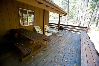 a porch of a cabin with a picnic table and chairs at 47R Altitude Adjustment in North Wawona