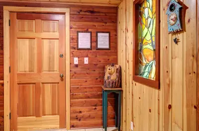 a door and a stool in a room with wooden walls at 57 The Williams Cabin in Wawona