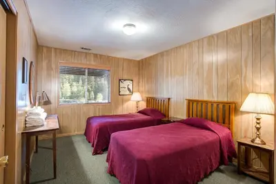 two beds in a room with wood paneling at 64 River Lodge in North Wawona