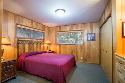 a bedroom with a bed and wooden walls at 64 River Lodge in North Wawona