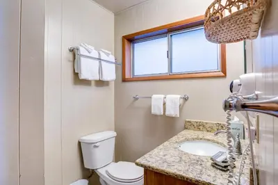 a bathroom with a toilet and a sink and a window at 64 River Lodge in North Wawona