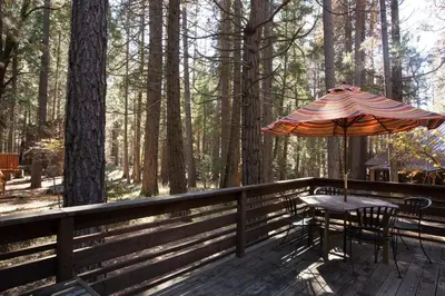 a wooden deck with a table and an umbrella at 53 Creekside Cabin in Wawona